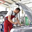 car mechanic in work clothes checks engine from a car in a workshop