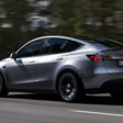 Tesla Model Y Metallic-Silber auf der Straße mit Wald im Hintergrund