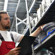 trade Business Shipping freight boxes goods storage High bay stock rack Architecture building interior company parts man car worker spare warehouse service automobile shop auto occupation mechanic professional technician male person workshop working work people distribution commercial depot checking checklist
