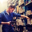 car service auto mechanic man tablet pc warehouse spare parts repair workshop smith maintenance automobile station shop master worker professional people person male concept motor vehicle transport profession occupation business mechanical technician indoors latin hispanic young automotive gadget computer technology app application connection online internet looking searching stillage shelf spares