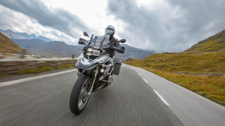Motorbiker riding in Austrian Alps, dramatic sky. Travel and freedom, outdoor activities