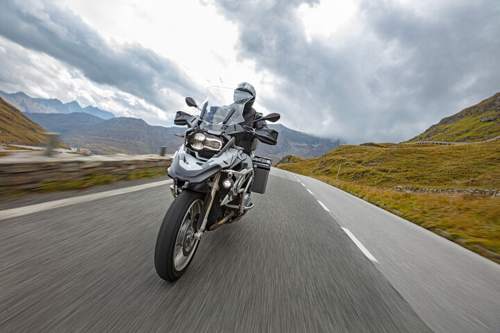 Motorbiker riding in Austrian Alps, dramatic sky. Travel and freedom, outdoor activities